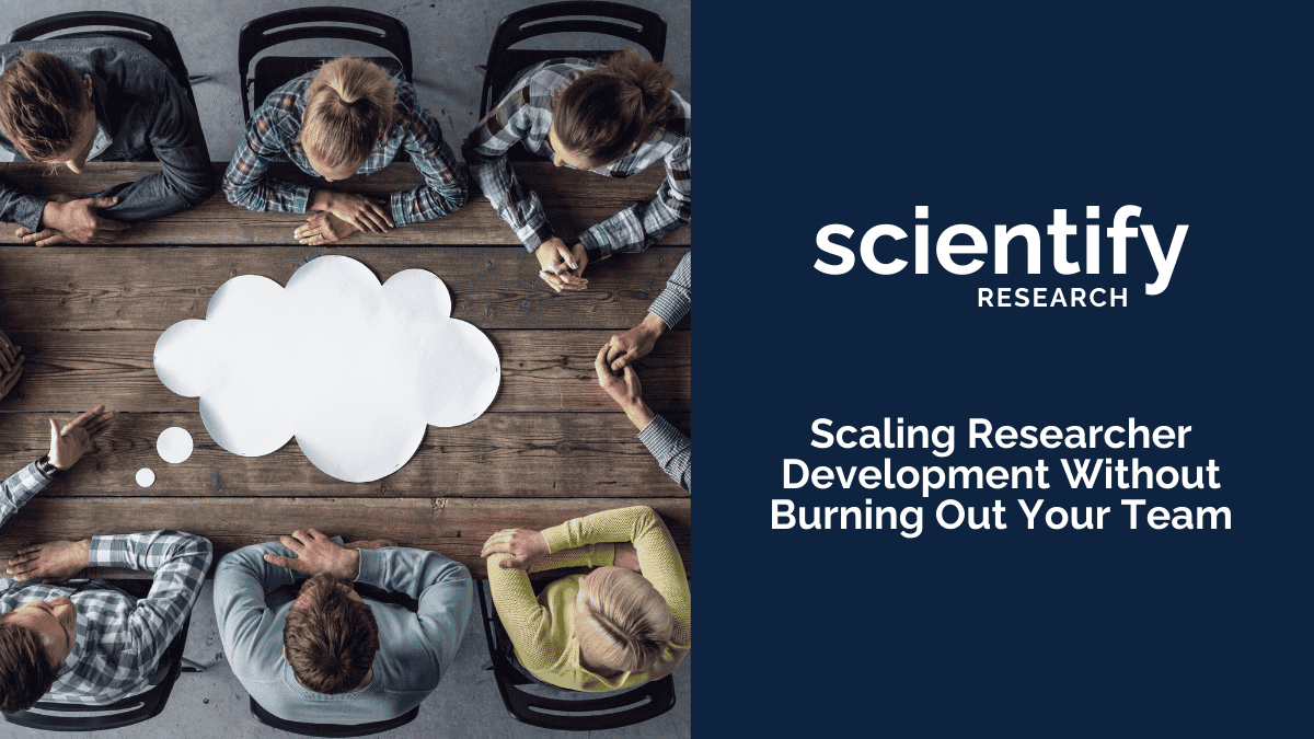Overhead view of a group of people seated around a wooden table with a cloud-shaped speech bubble in the center. On the right side, a blue panel displays the Scientify Research logo and the text “Scaling Researcher Development Without Burning Out Your Team.”